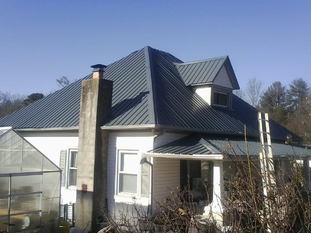 Dark blue standing seam metal roof on a white farmhouse with dormer — Slate & Tile Roof Repair by Roofing Brothers in Valley