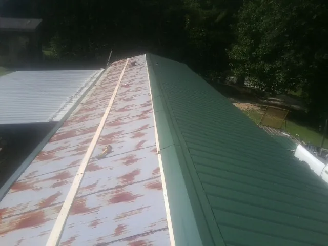 Old rusted panels beside newly installed green metal roofing — Wind Damage Roof Repair by Roofing Brothers in Valley