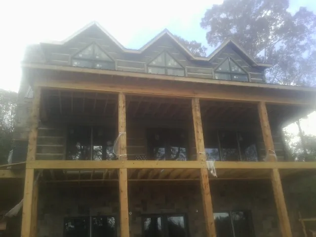 Dormers and porch framing on a large log home under construction — Roof Coating work by our crew in Valley
